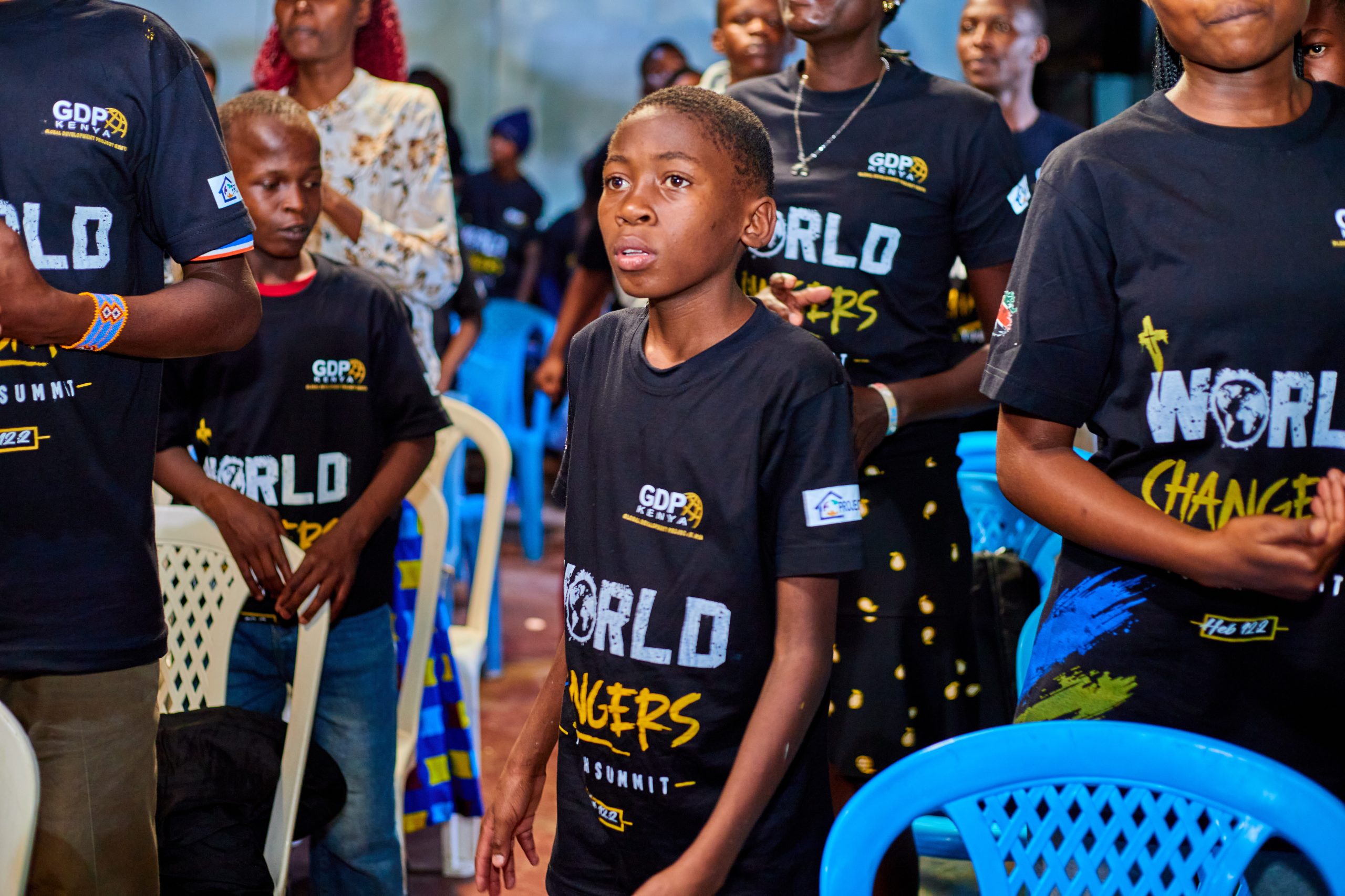 A young World Changer standing among peers, wearing his World Changers Youth Summit t-shirt