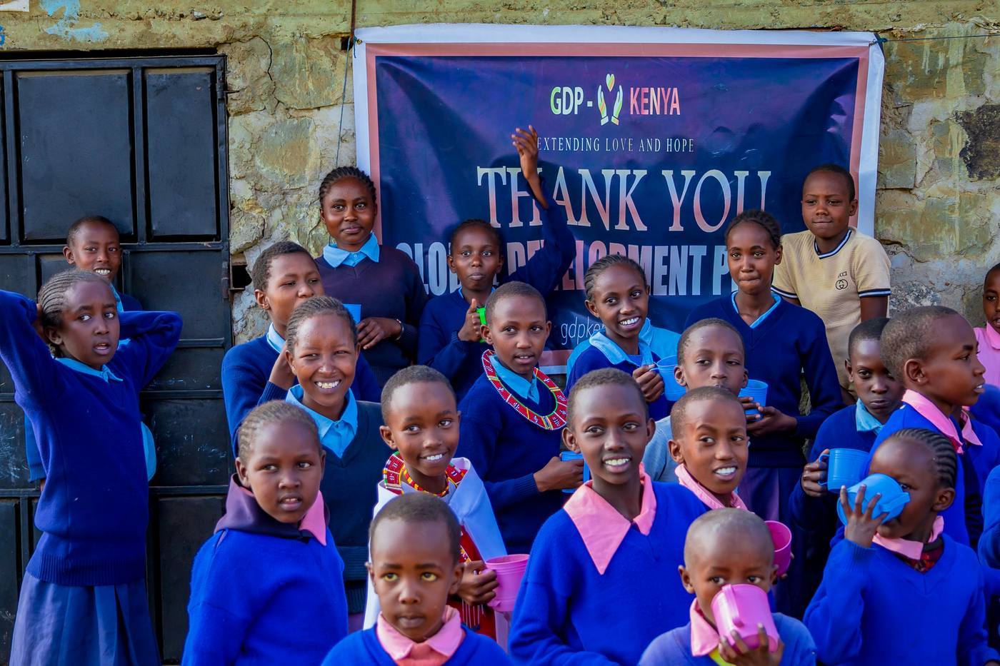 Students in school uniforms in front of a GDP Kenya thank-you banner