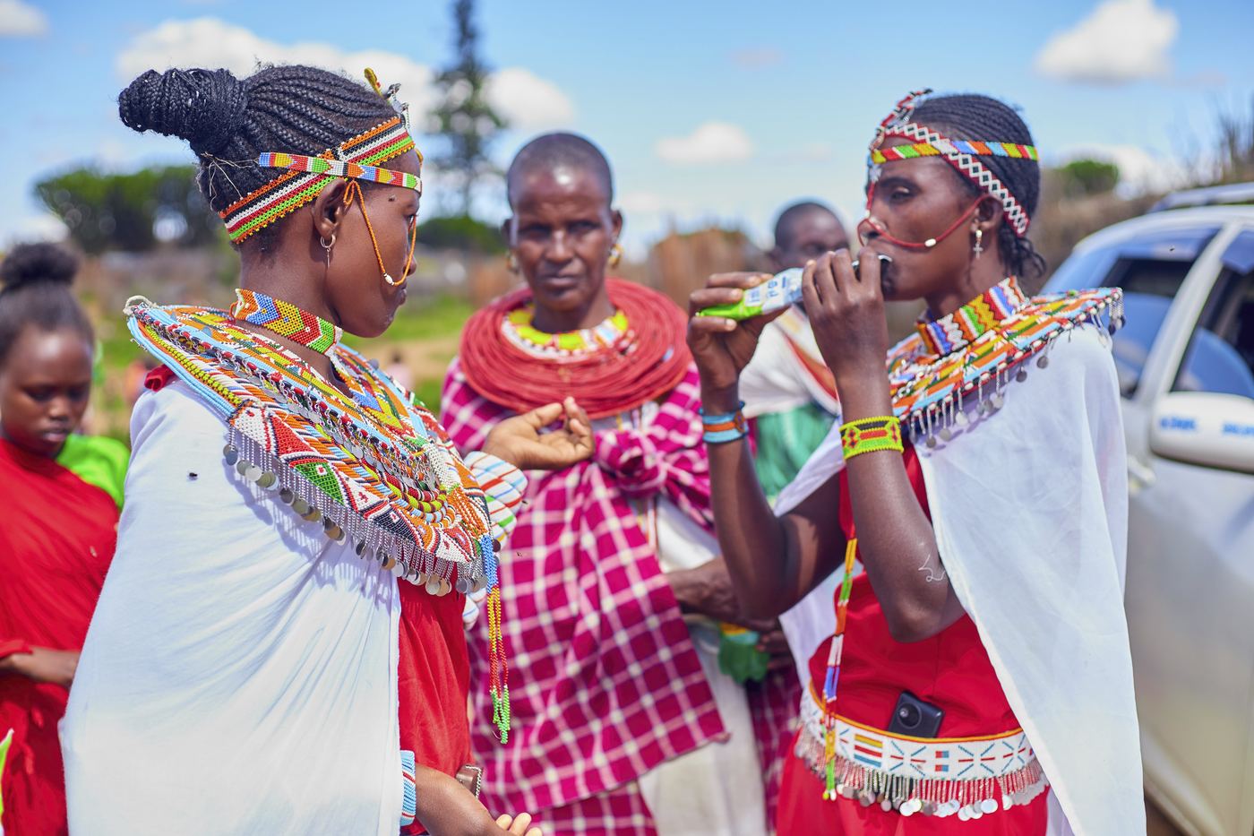 Samburu women in traditional beaded dress sharing a drink