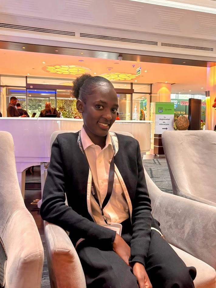 A young woman in professional attire smiling at a conference