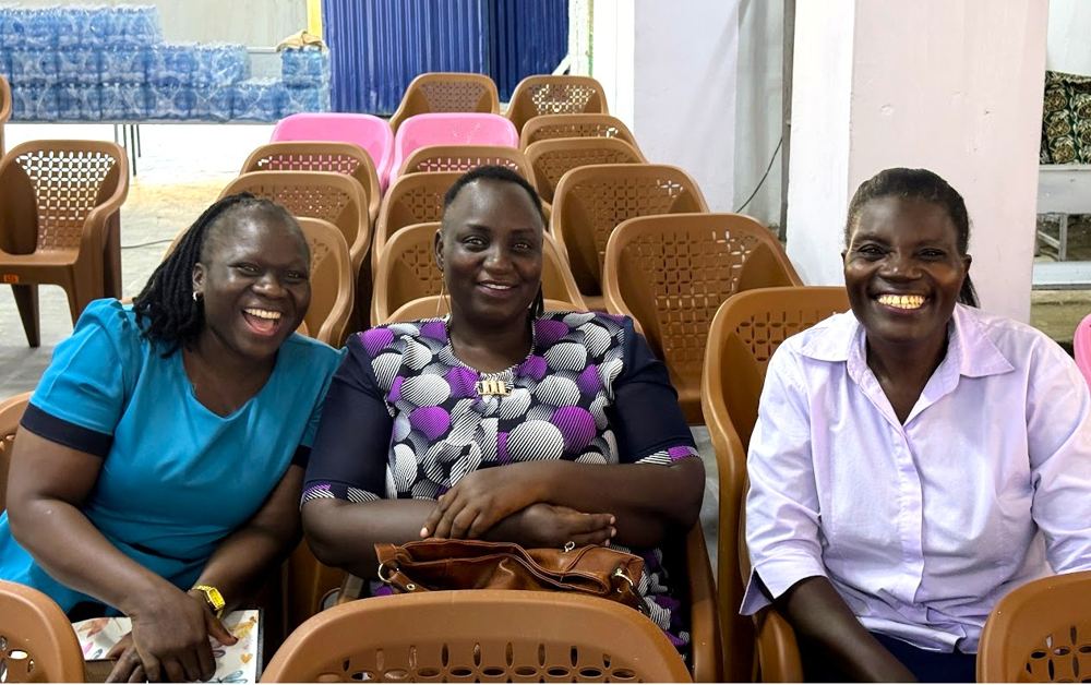 Three women smiling together in the auditorium at a GDP summit