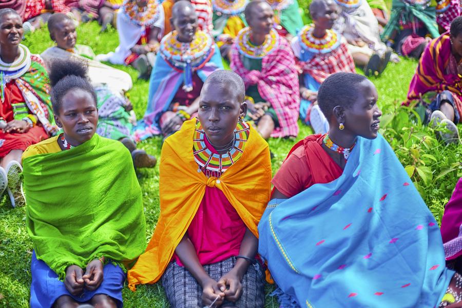 Three Samburu women in vibrant green, orange and blue traditional dress and beaded jewelry at GDP empowerment event, Northern Kenya