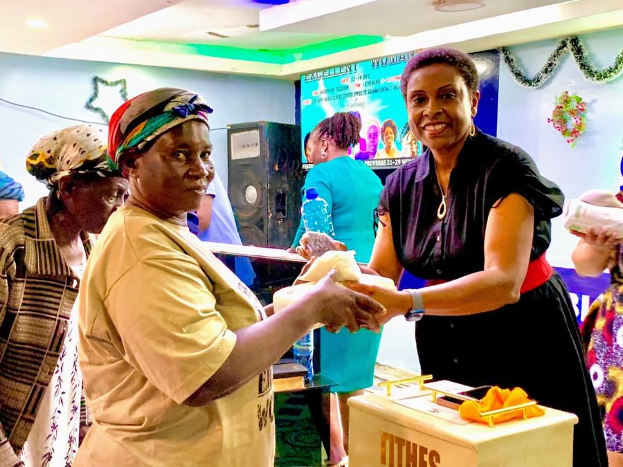 Woman receiving resources at GDP Excellent Woman Conference — Patricia Wright handing food package, Mombasa Kenya