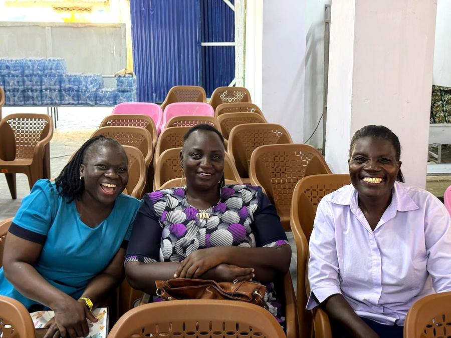 Three women laughing together at table inside GDP Multiplex Center — Mombasa Kenya women's conference
