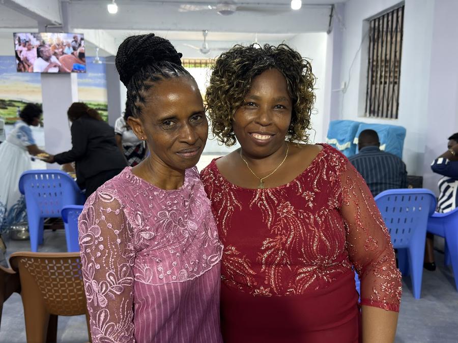 Two women in formal dress at GDP Women's conference — pink lace and red beaded dress, Mombasa Kenya