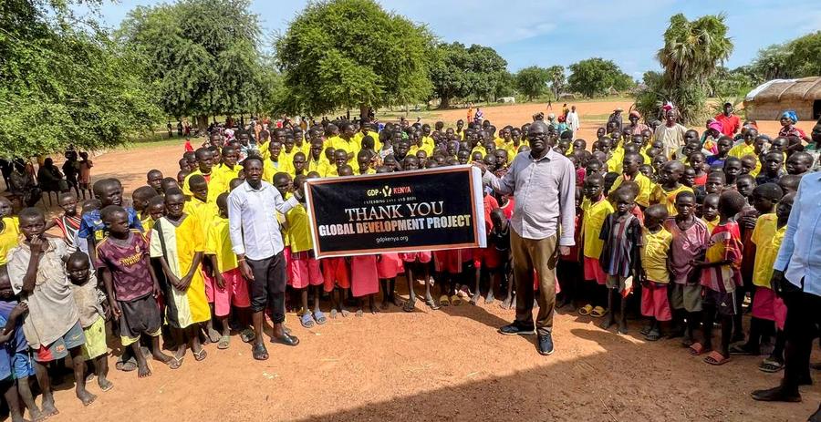 Hundreds of children in yellow shirts holding GDP Kenya Thank You banner — humanitarian aid, East Africa