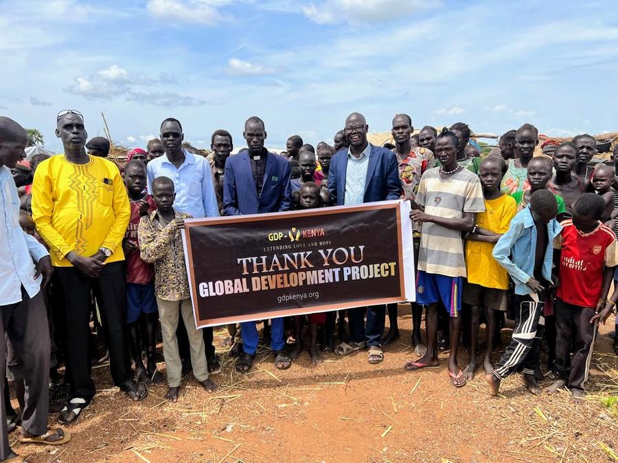 Community leaders and villagers holding GDP Kenya Thank You banner — humanitarian aid outreach, East Africa