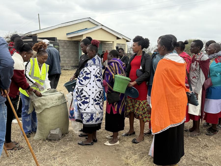 GDP team member in yellow safety vest distributing grain and food to line of women — Samburu/Maasai community, Kenya